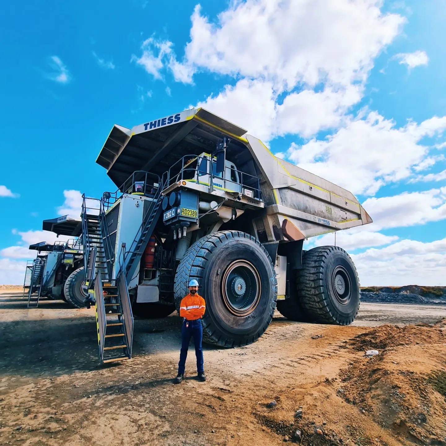Ultra-class rear dump haul trucks parked in line with an engineer standing in front